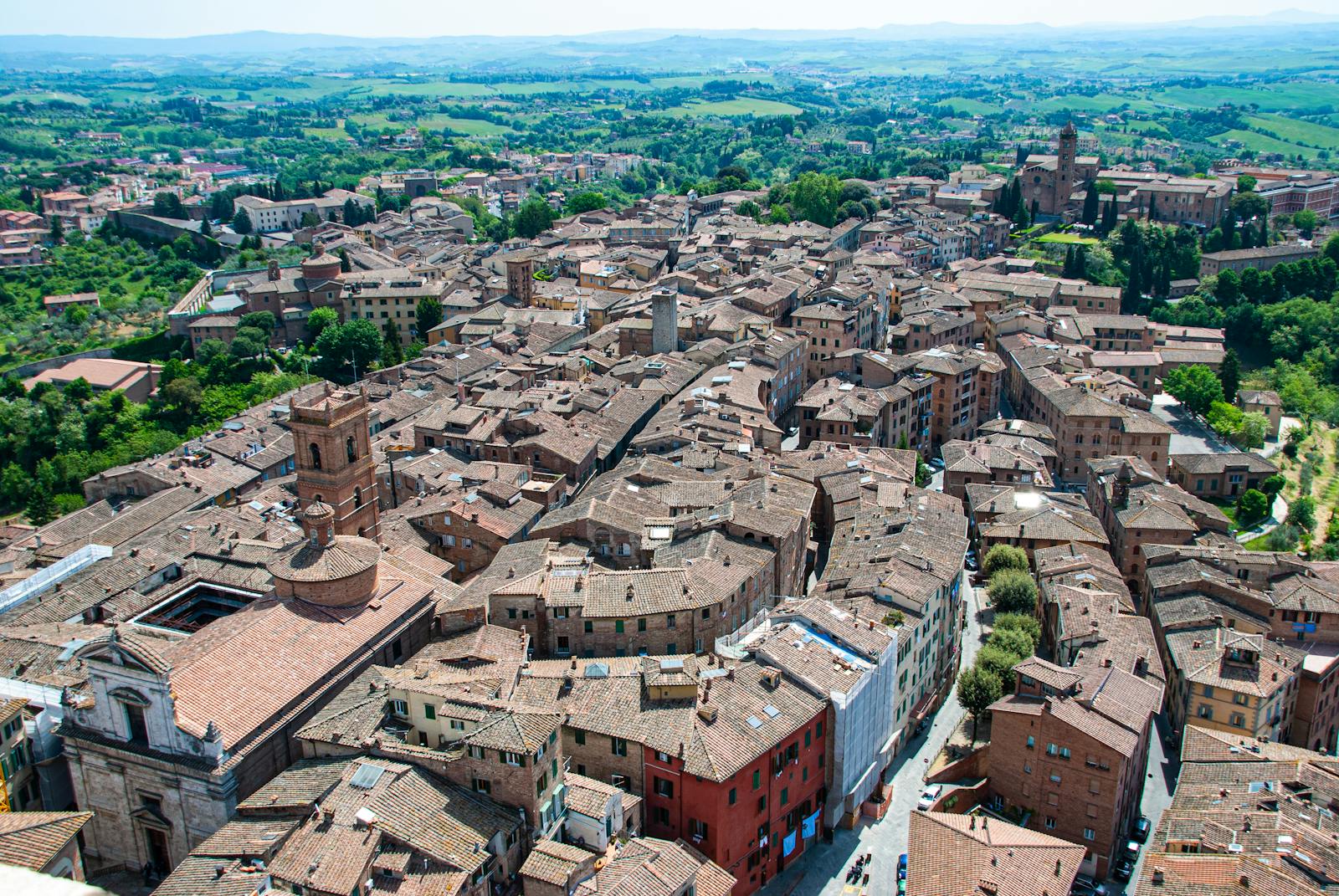 Beautiful aerial shot of Siena's historic rooftops amidst lush Tuscany landscapes.